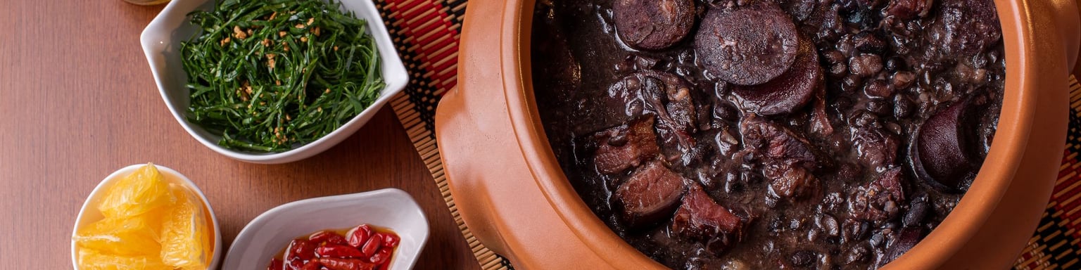 A bowl of feijoada with the traditional accompaniments