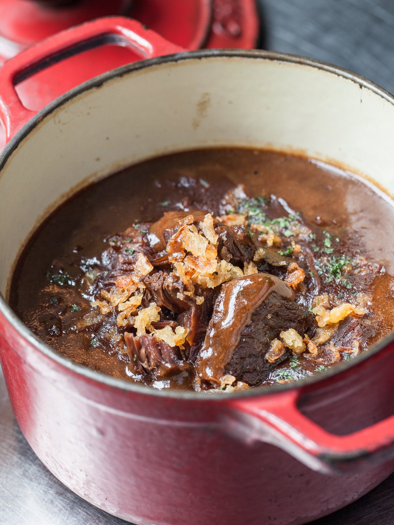 Flemish stew in a casserole dish with basket of French fries