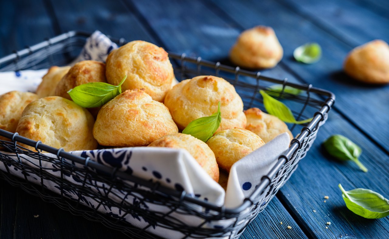 Gougères in a basket with basil leaves