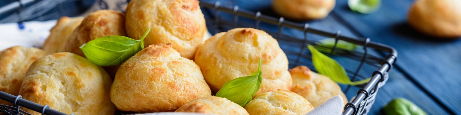 Gougères in a basket with basil leaves