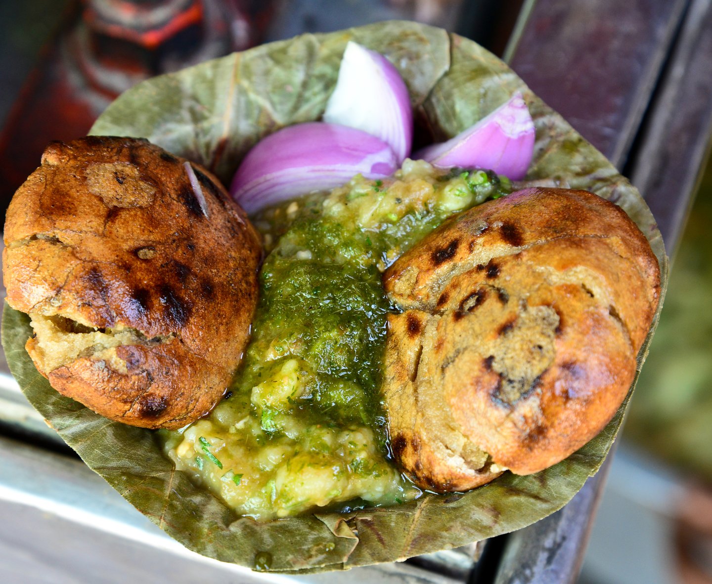 A bowl of baati chokha garnished with red onion.