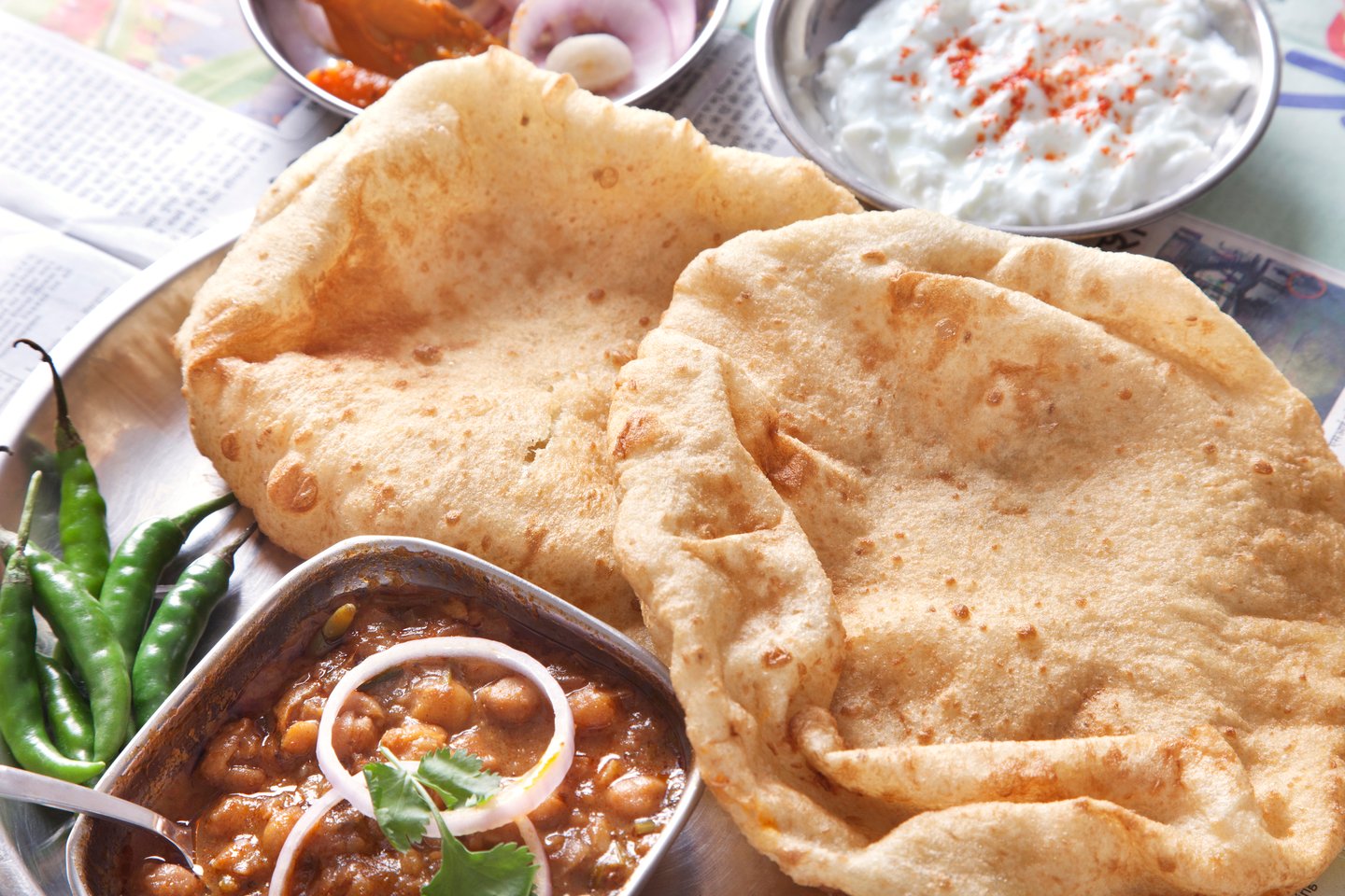 A platter of Chole Bhature with accompanying sauces in the background