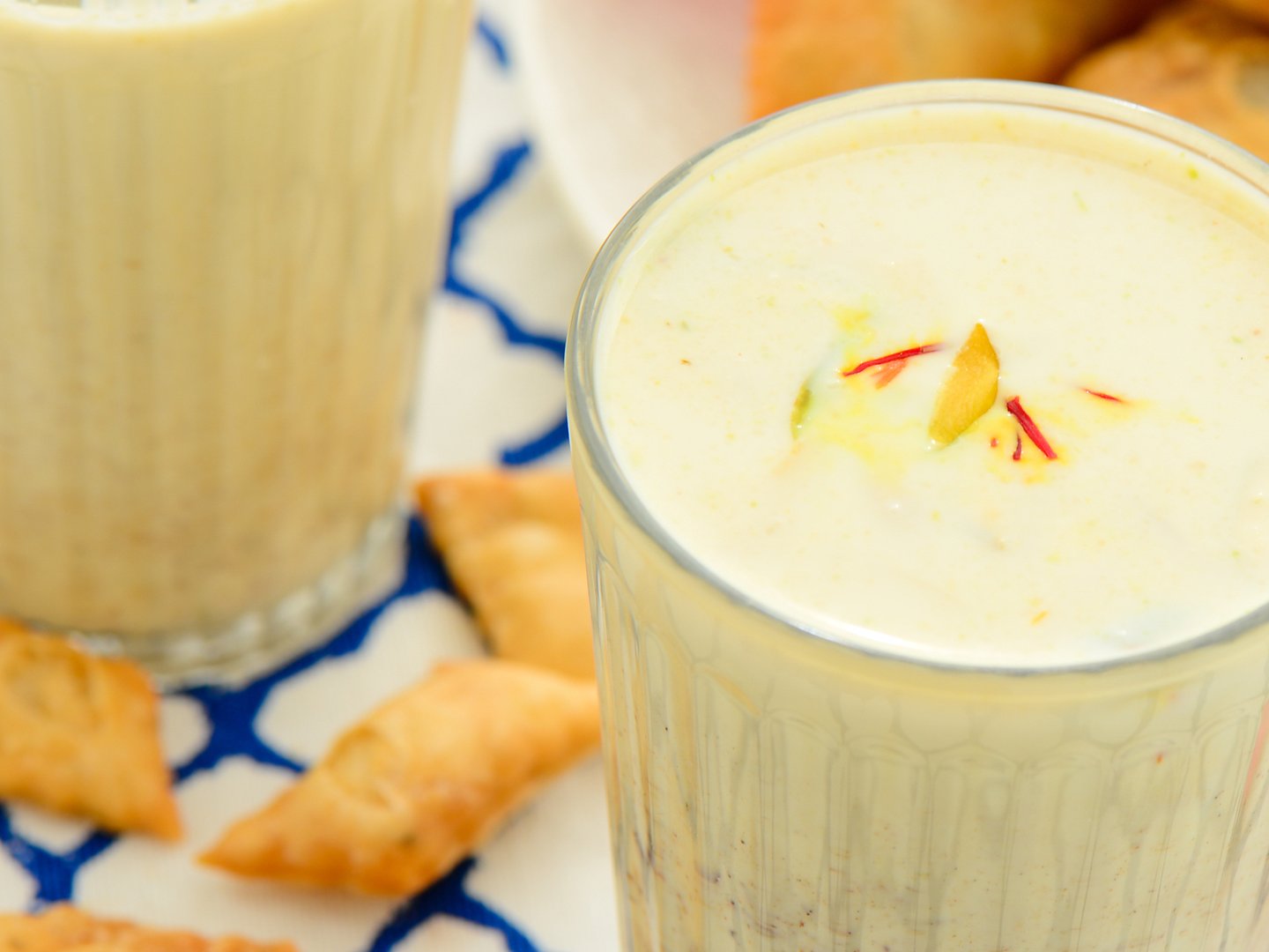 A glass of thandai garnished with saffron.