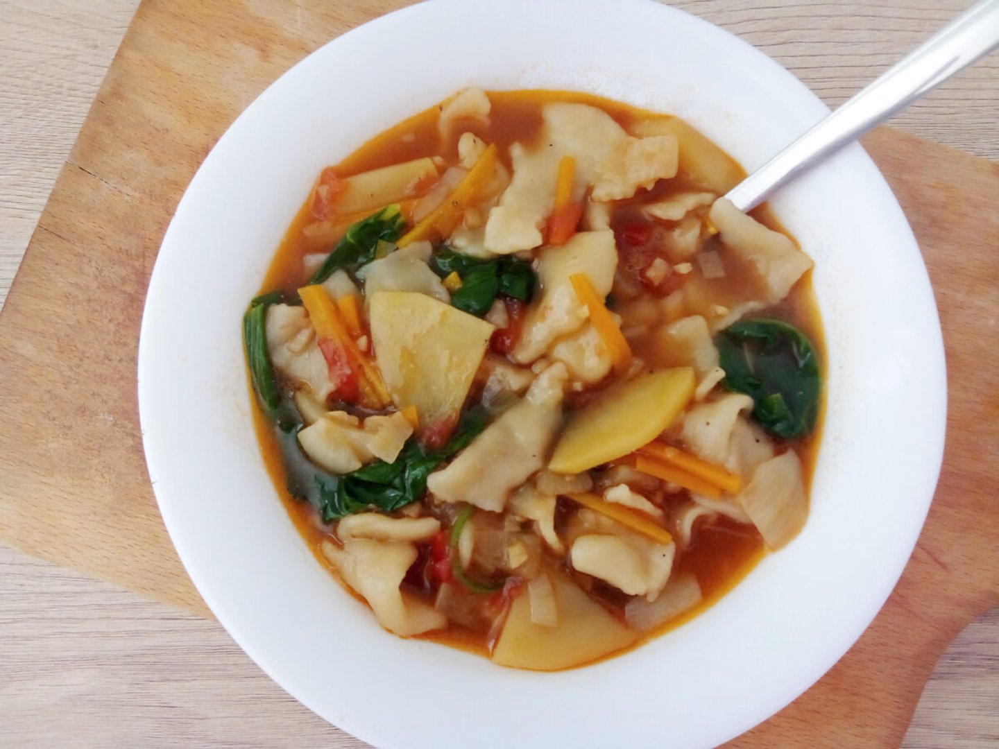 A bowl of thentuk - Tibetan pulled noodles - on a board