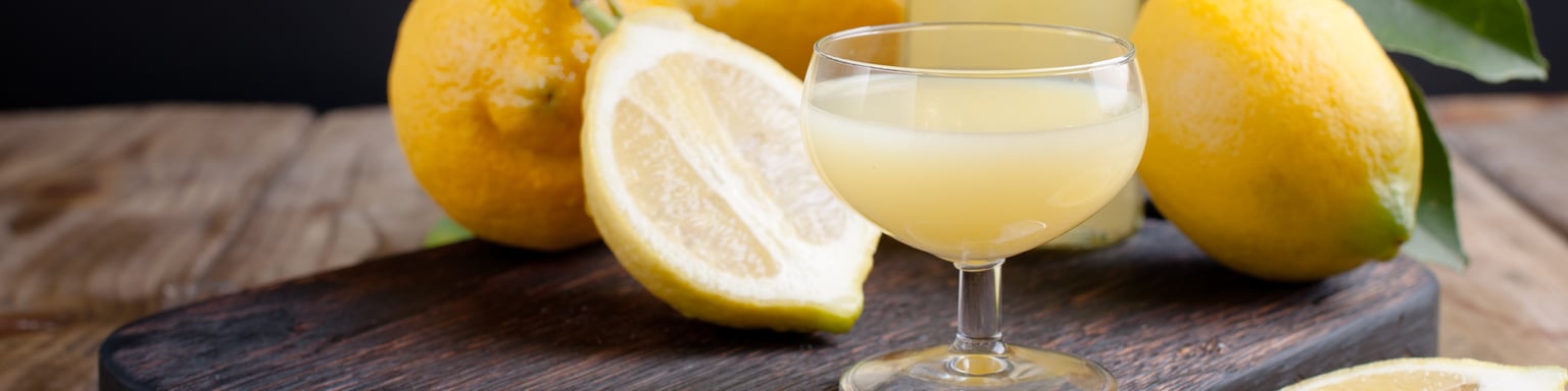 A glass of limoncello with lemons on a chopping board