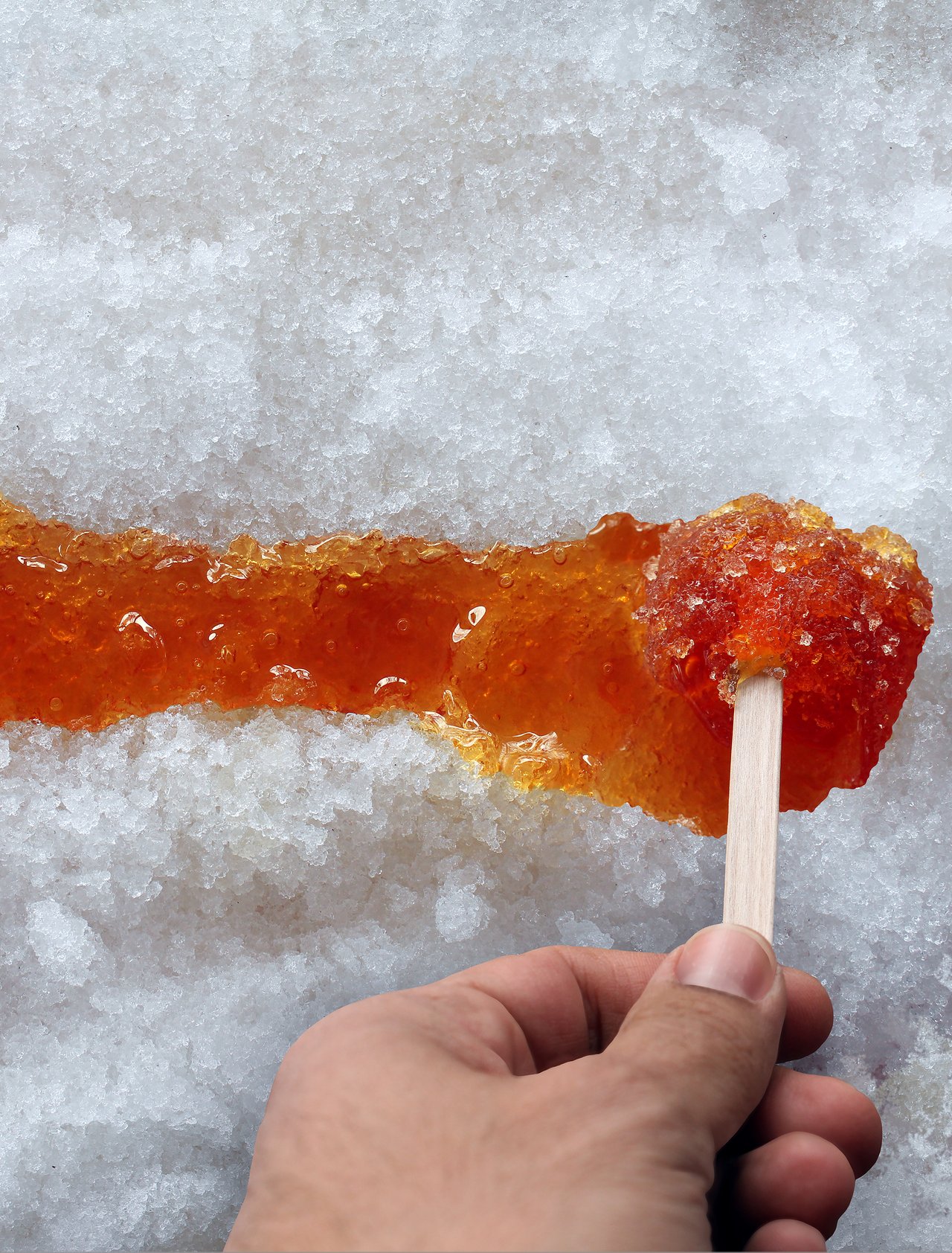 Spreading maple taffy along the snow with a stick