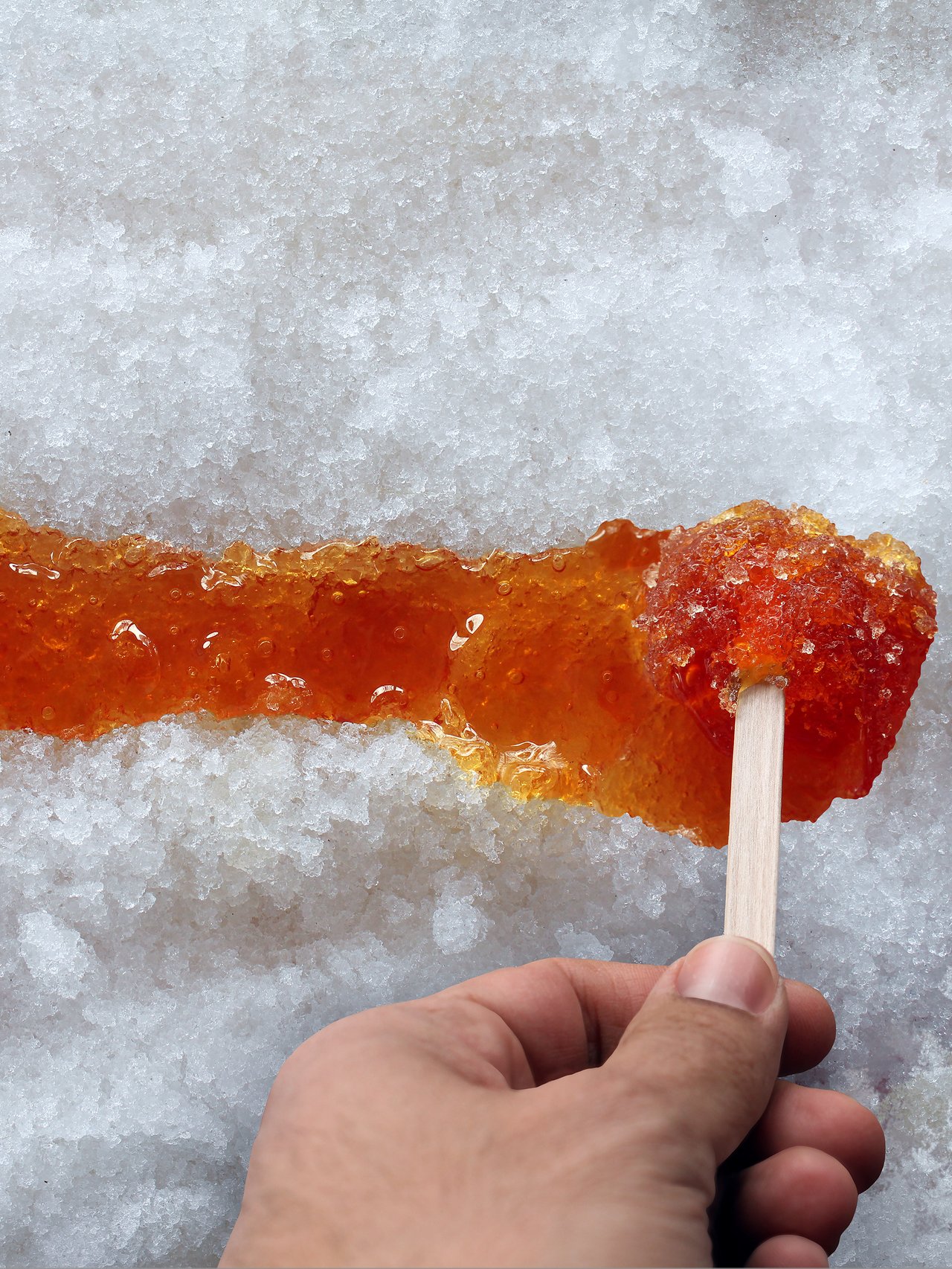Spreading maple taffy along the snow with a stick