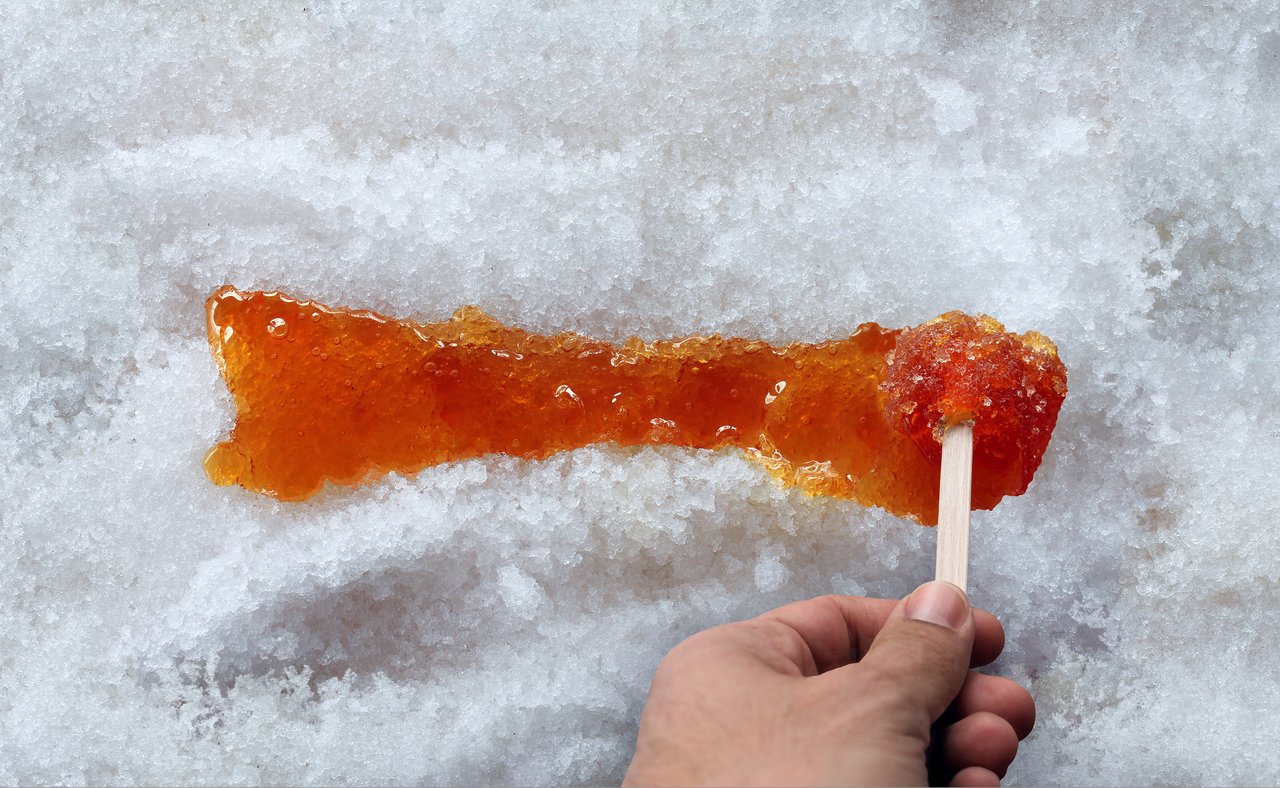 Spreading maple taffy along the snow with a stick