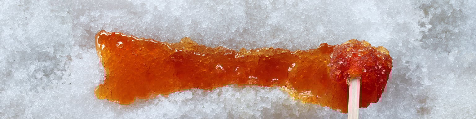 Spreading maple taffy along the snow with a stick