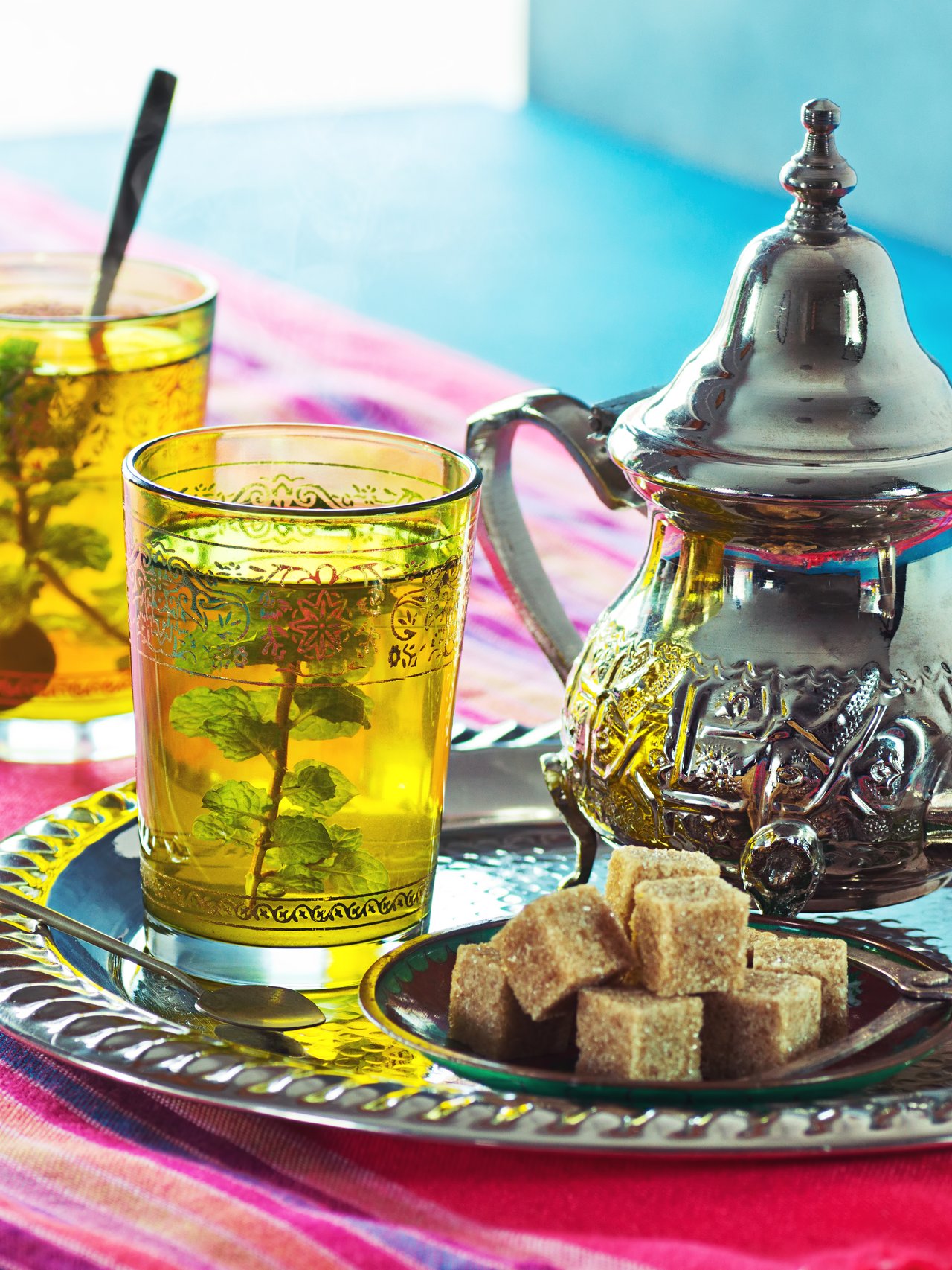 Two cups of Moroccan mint tea with a traditional teapot and sugar cubes
