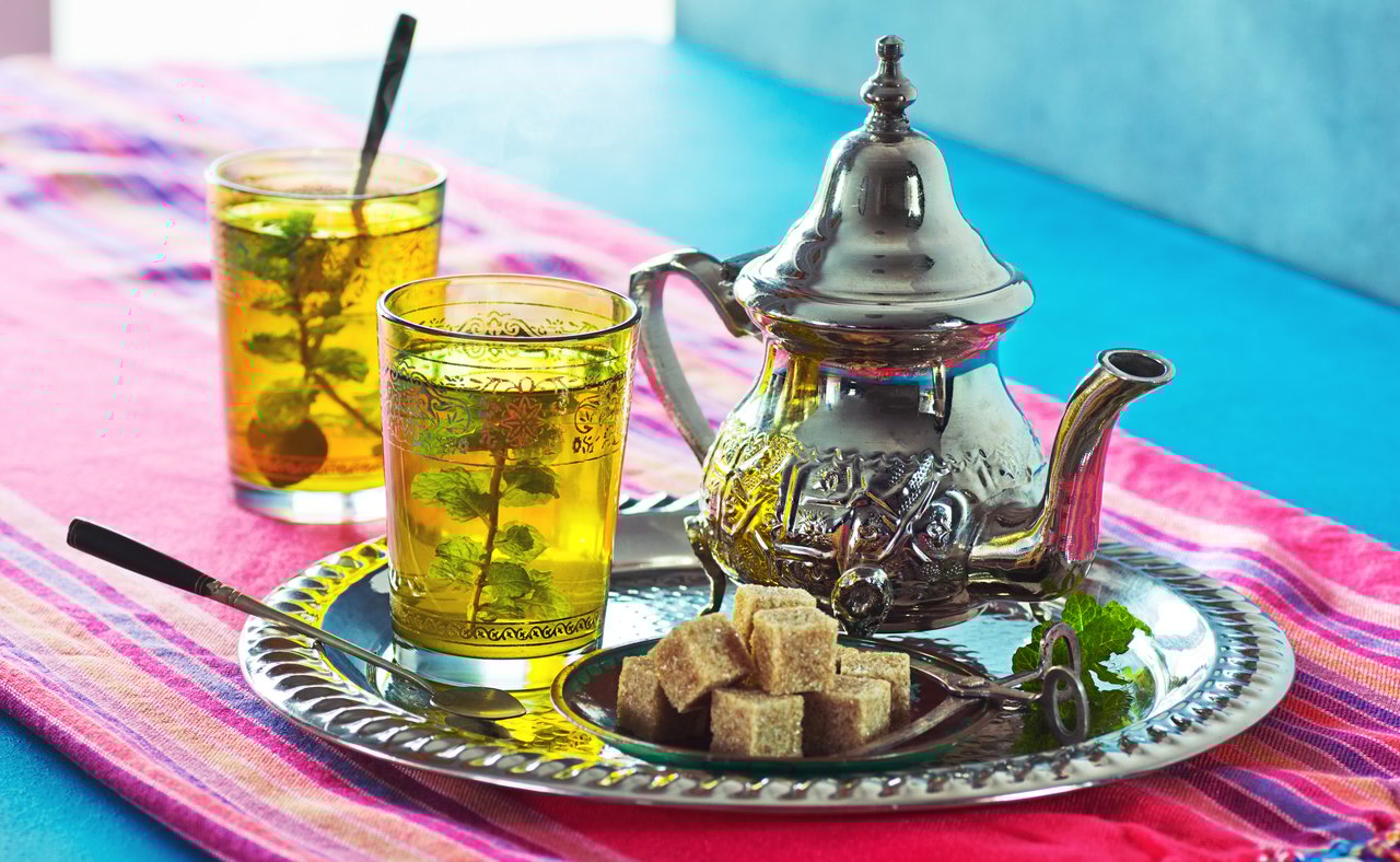 Two cups of Moroccan mint tea with a traditional teapot and sugar cubes
