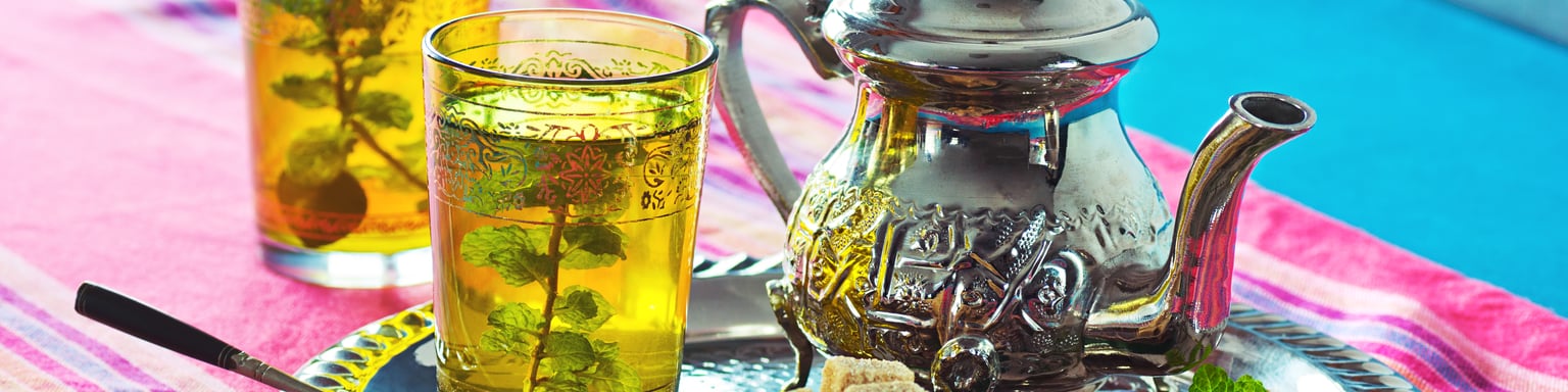 Two cups of Moroccan mint tea with a traditional teapot and sugar cubes