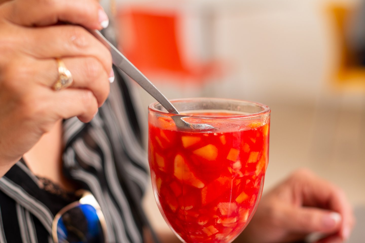 A woman eating fruit from a salpicon, a Colombian fruit cocktail
