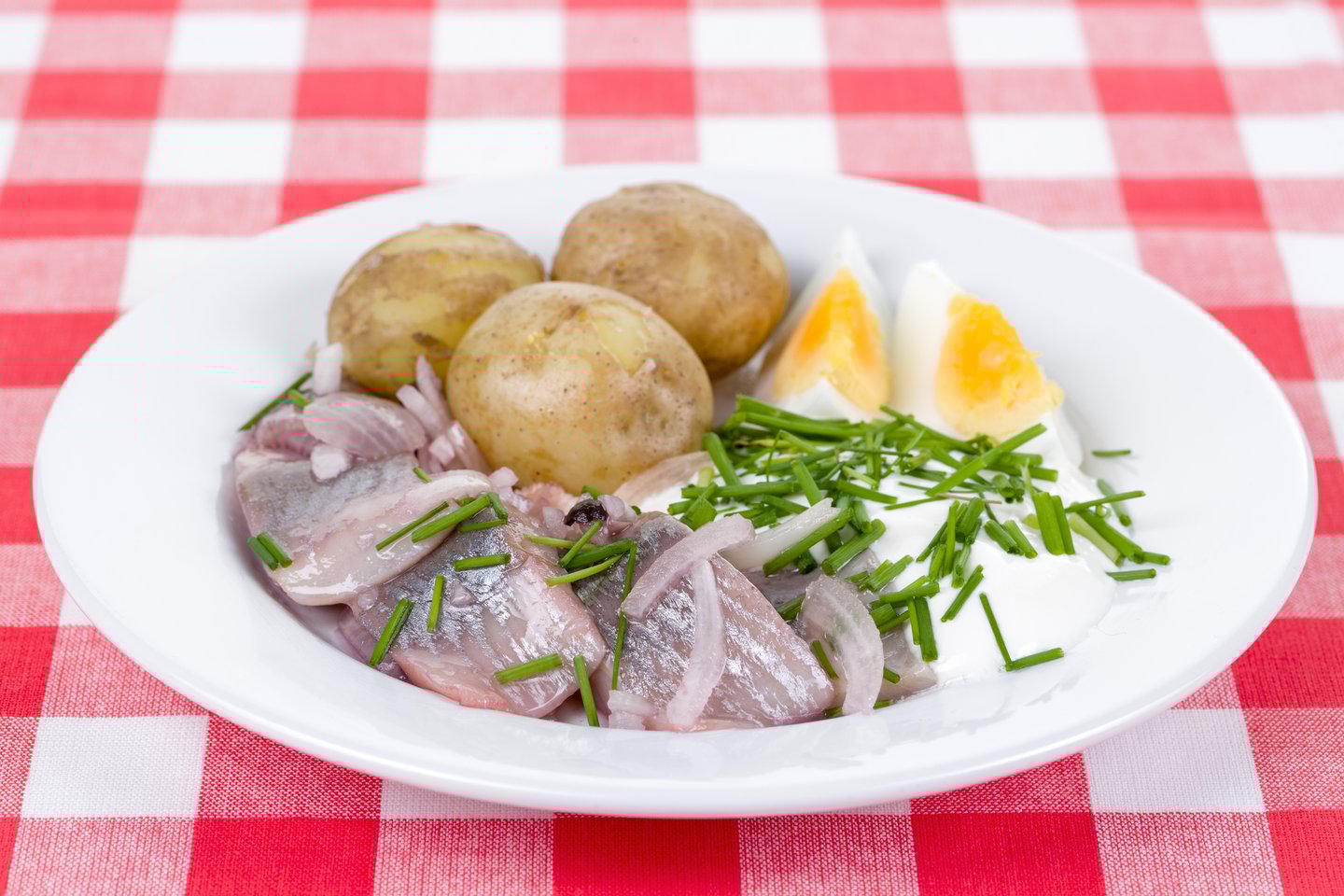 Pickked herring served with boiled potatoes, sour cream, chives and eggs