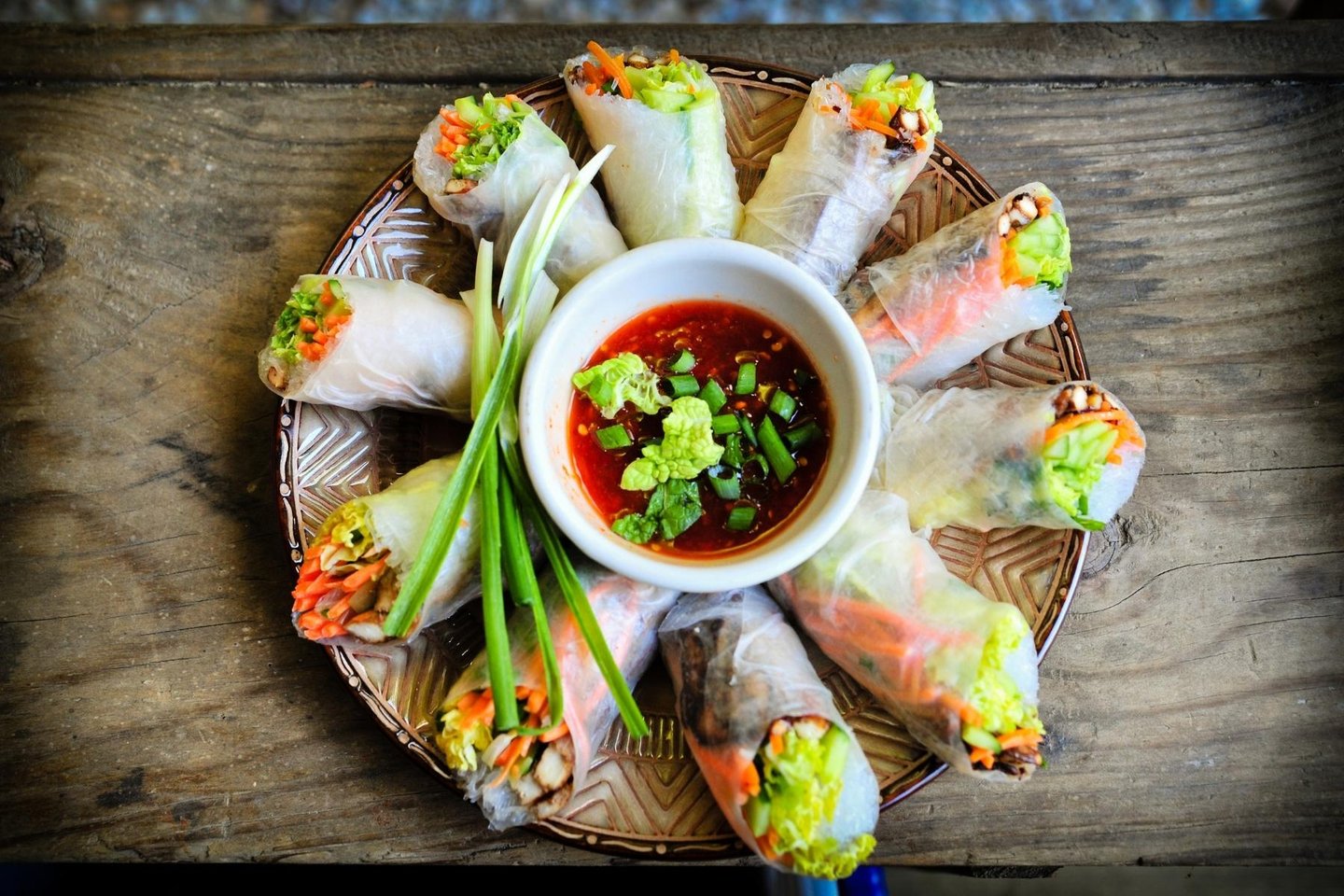 Vietnamese spring rolls arranged on a plate with a bowl of sauce in the middle