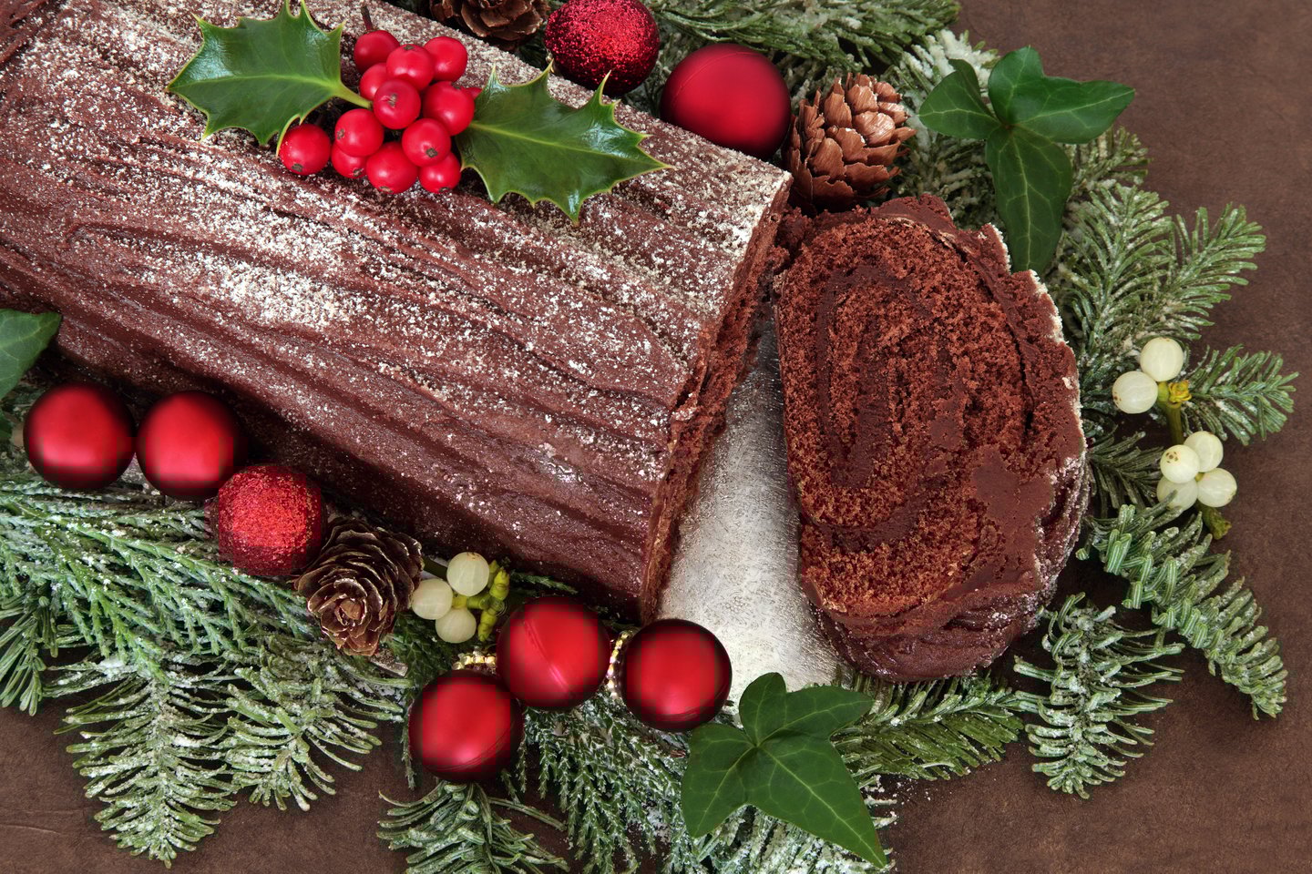 A bûche de noël or Yule log surrounded with Christmas decorations