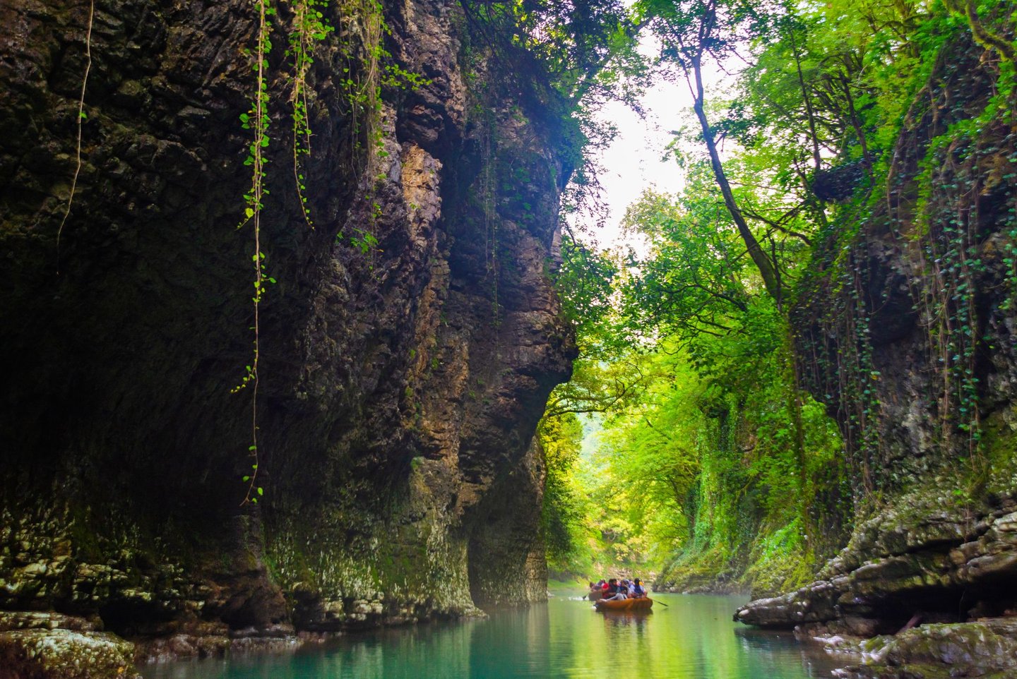 A boat floating between the huge walls of the Martvili Canyon in Georgia.