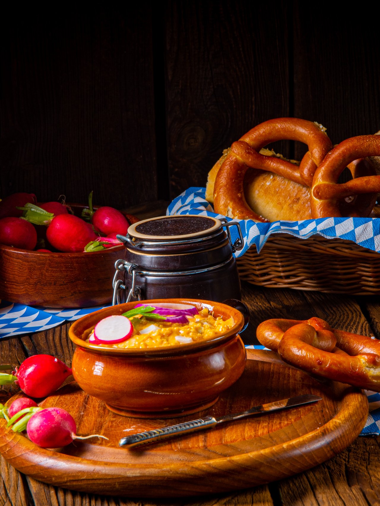 Rustic Bavarian obatzda garnished with radishes and served with beer and pretzels