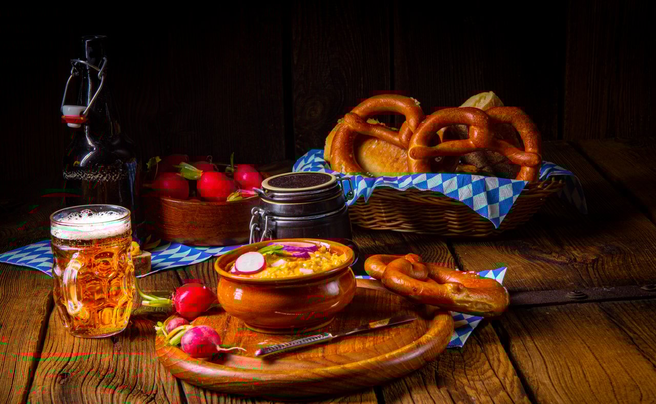 Rustic Bavarian obatzda garnished with radishes and served with beer and pretzels