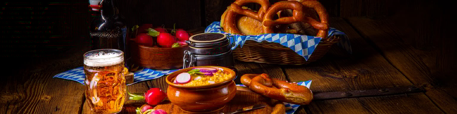Rustic Bavarian obatzda garnished with radishes and served with beer and pretzels