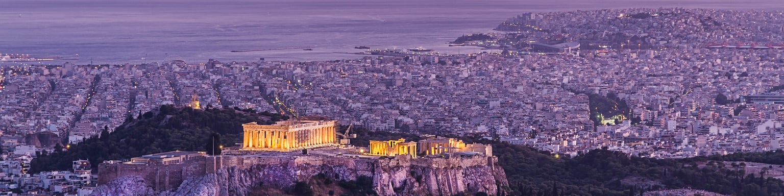 The Acropolis at night surrounded by the city of Athens.