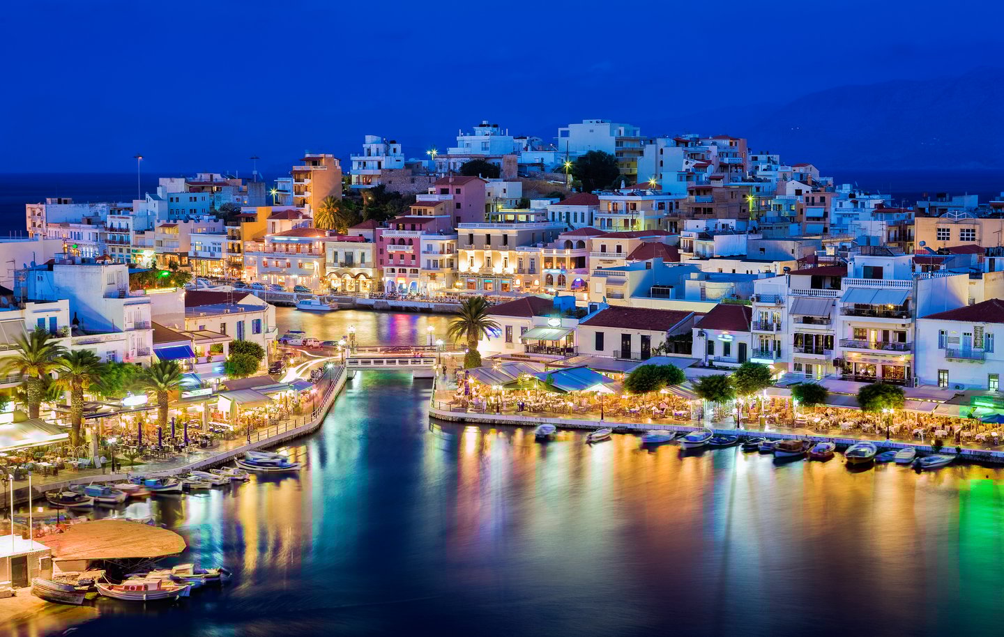 The lights of Agios Nikolaos reflecting in the water at night