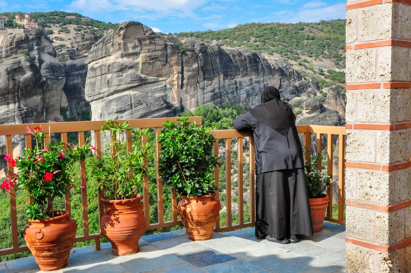 A nun enjoying the view from a balcony in Meteora, Greece.