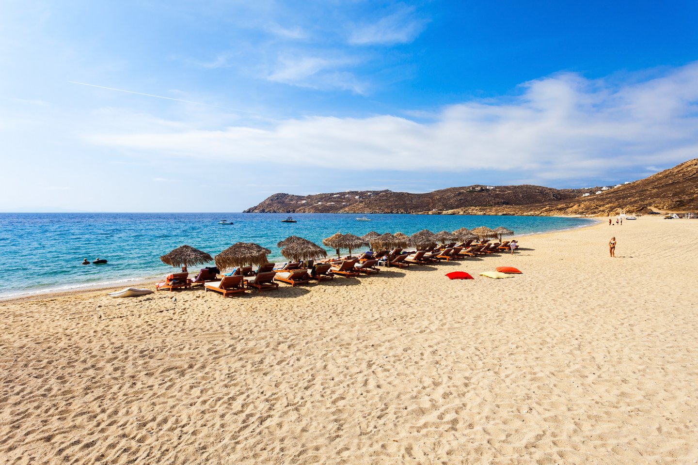 Sun umbrellas and pillows on the white sand of Elia Beach on Mykonos, Greece