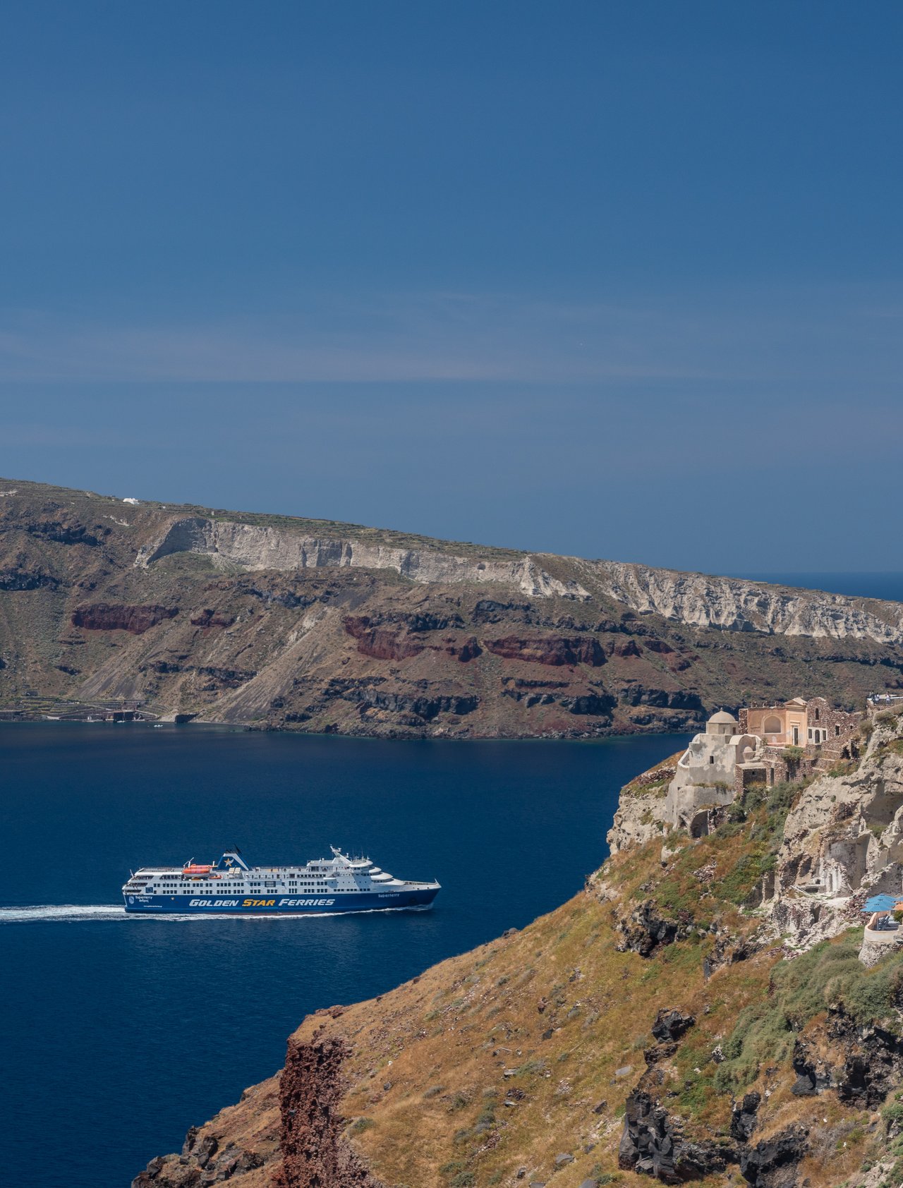 A ferry passing by Oia's cliffs in Santorini