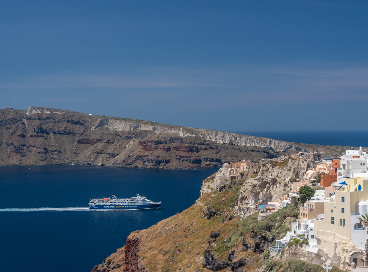 A ferry passing by Oia's cliffs in Santorini