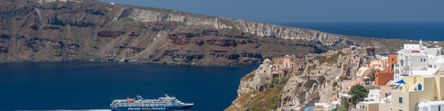 A ferry passing by Oia's cliffs in Santorini