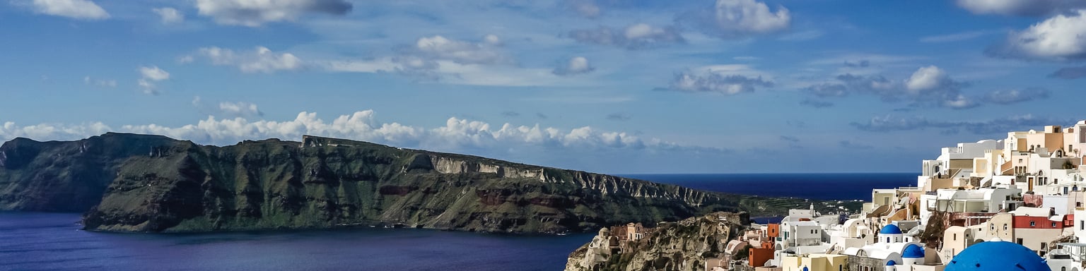 Blue and white rooftops in Santorini with the caldera in the background