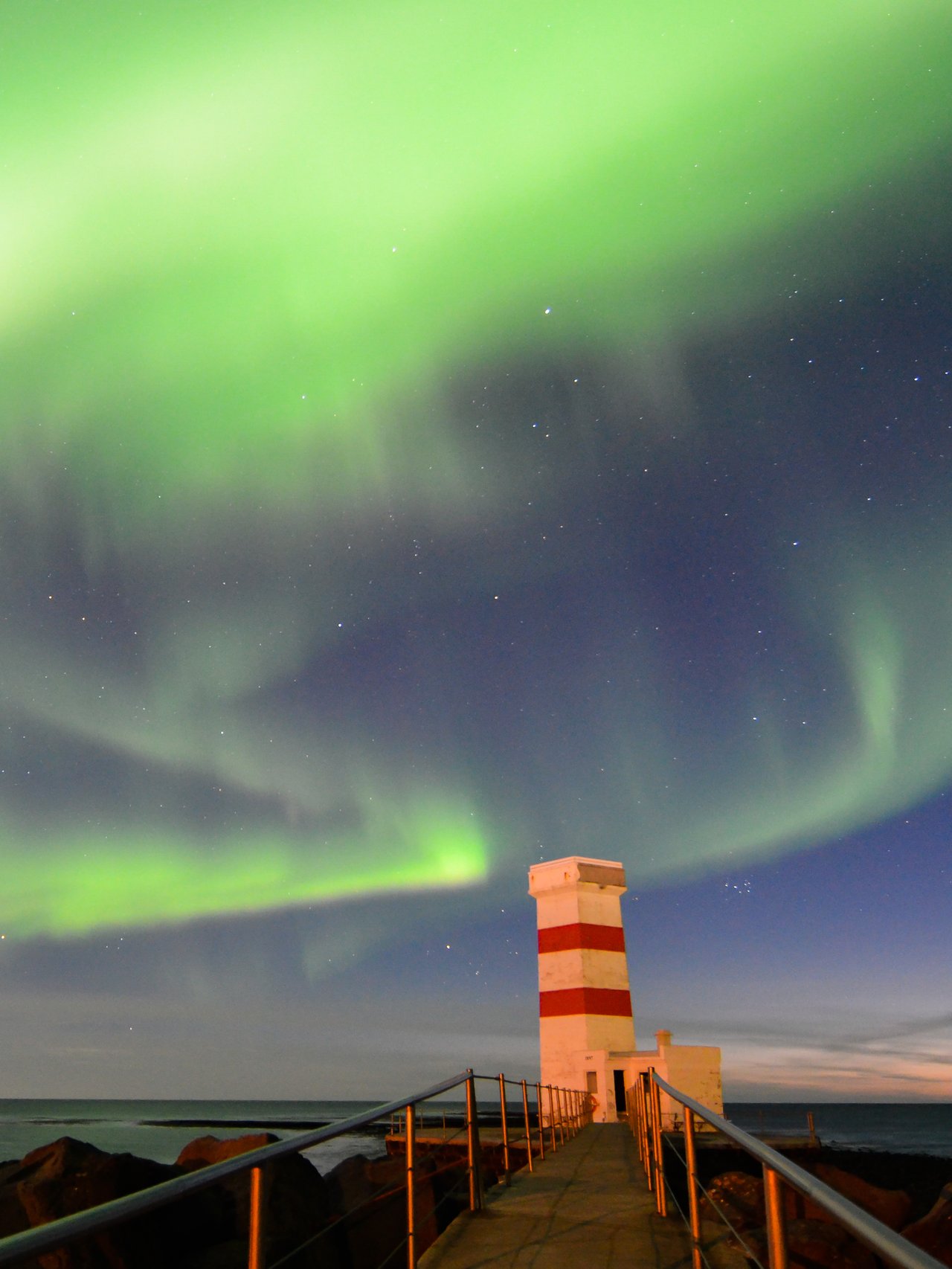 The Northern Lights visible over the Old Garður Lighthouse in Reykjanes, Iceland