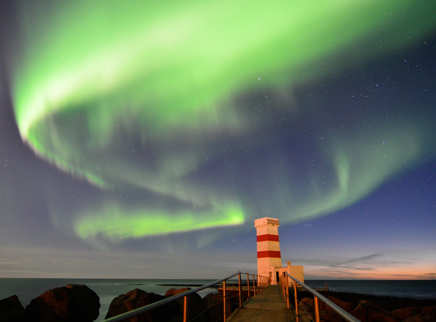 The Northern Lights visible over the Old Garður Lighthouse in Reykjanes, Iceland