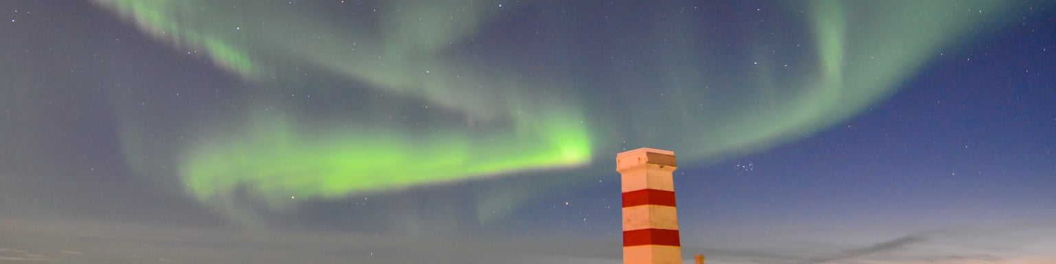 The Northern Lights visible over the Old Garður Lighthouse in Reykjanes, Iceland