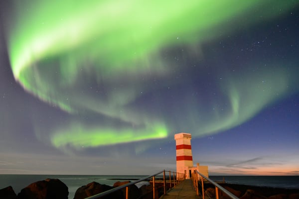 The Northern Lights visible over the Old Garður Lighthouse in Reykjanes, Iceland