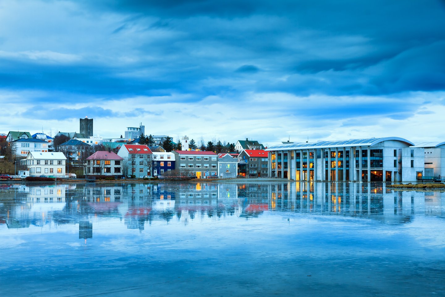 Beautiful reflection of the cityscape of Reykjavik in lake Tjornin at the blue hour in winter with the Basilica of Christ the King (Landakotskirkja) and the city hall