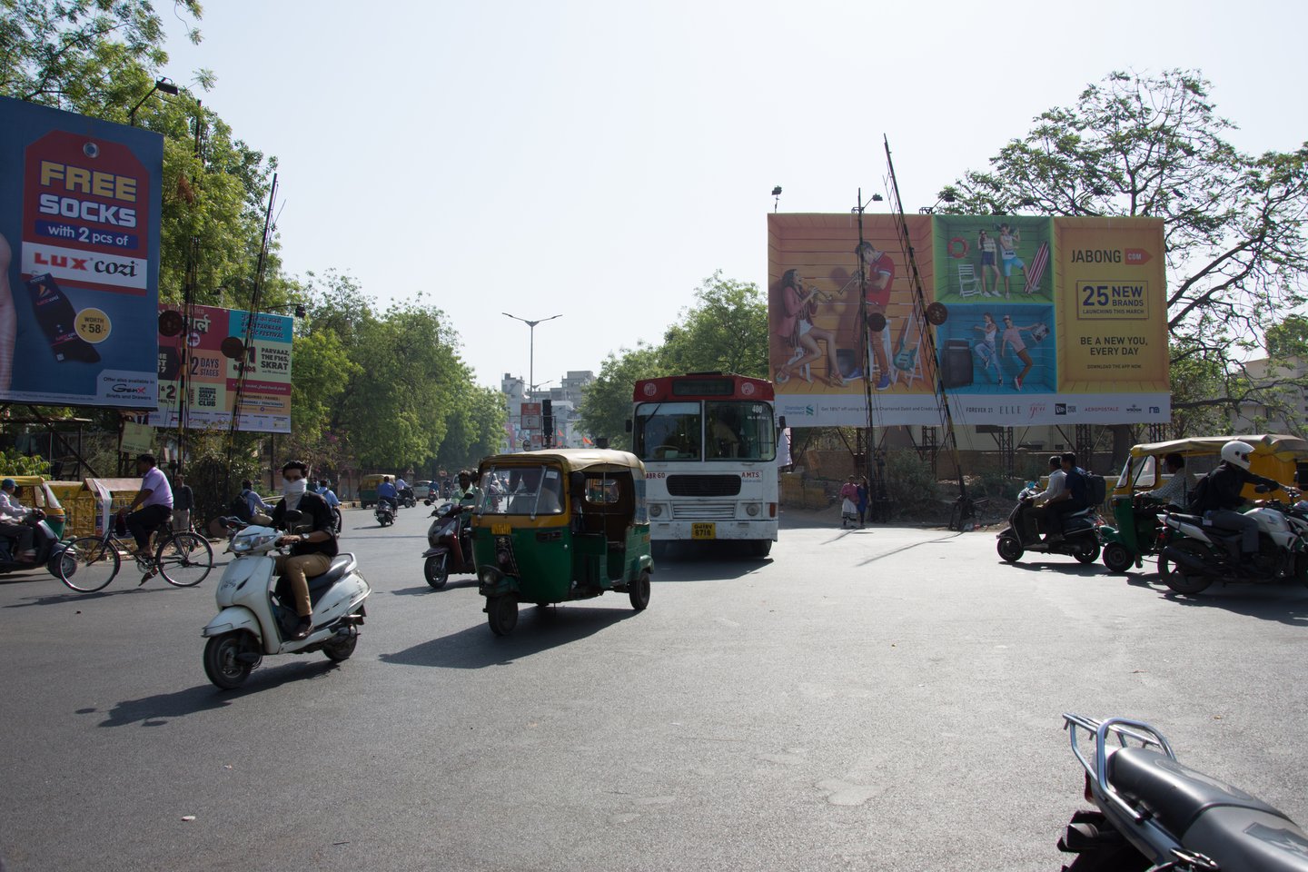 A tuk tuk, bus, motorcycle, bicycle and people on a street in Ahmedabad