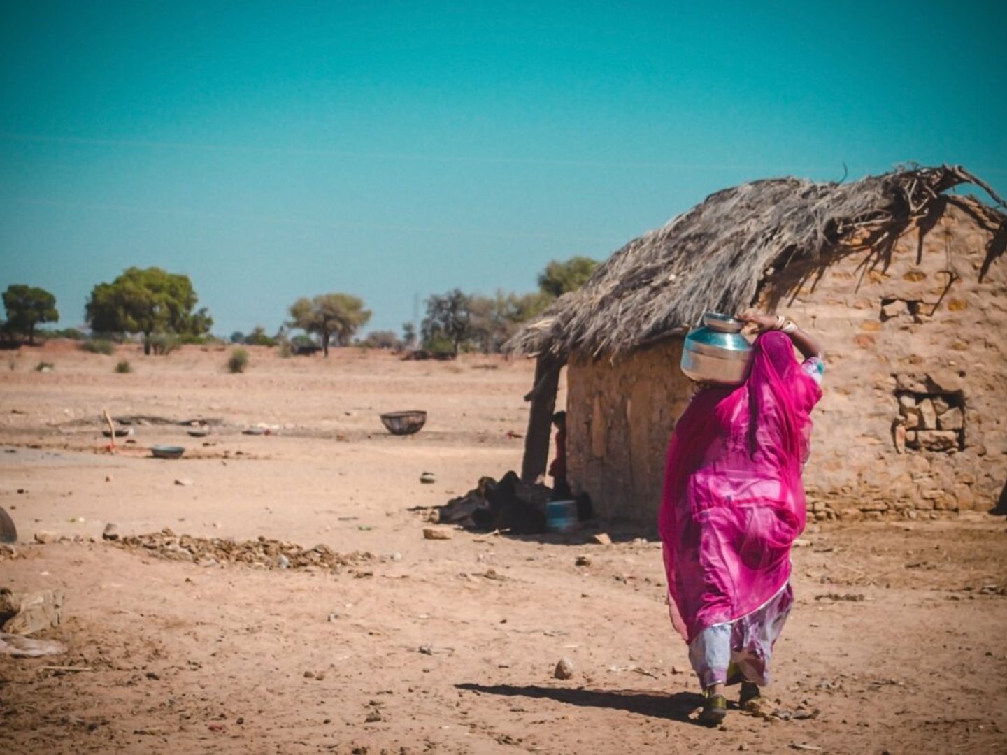 A woman by a hut in the desert in India