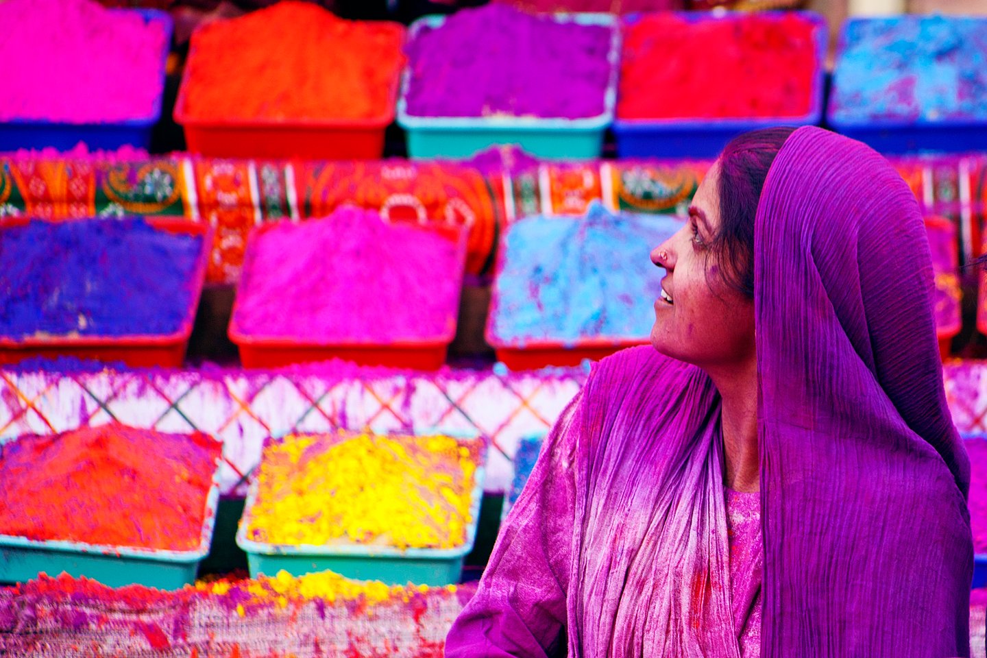 A woman covered in purple with containers of dye behind her