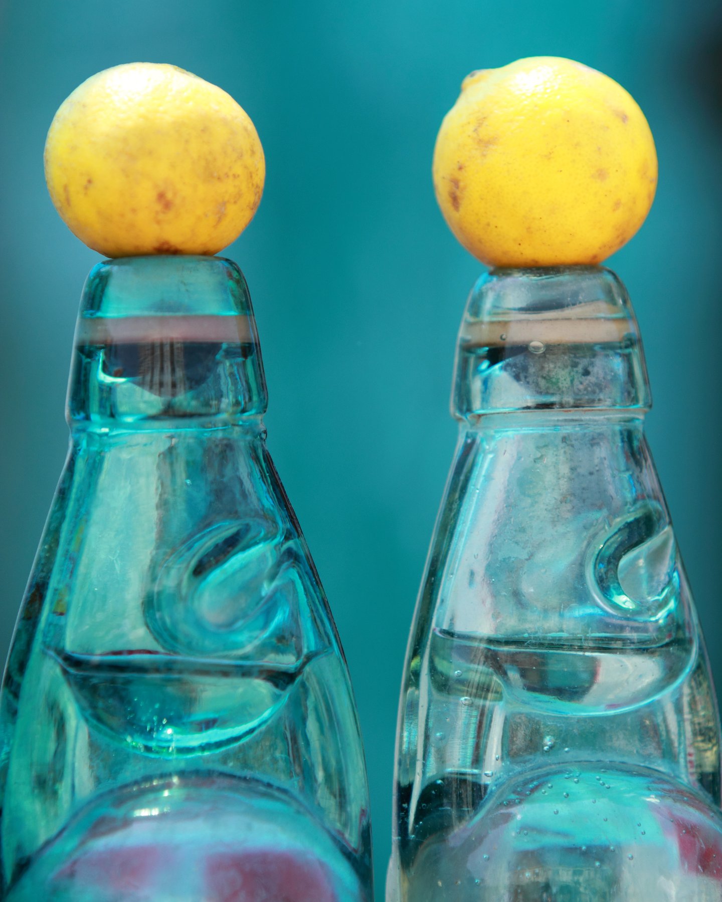 Lemon soda in bottles with lemon balancing on top
