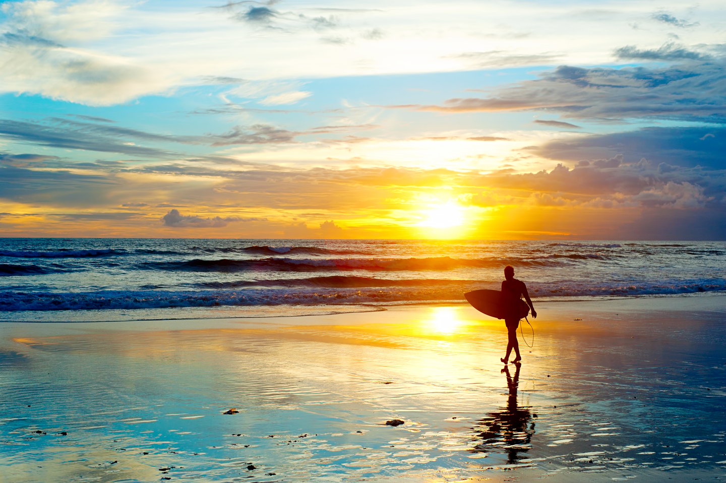 A surfer on a Balinese beach at sunset
