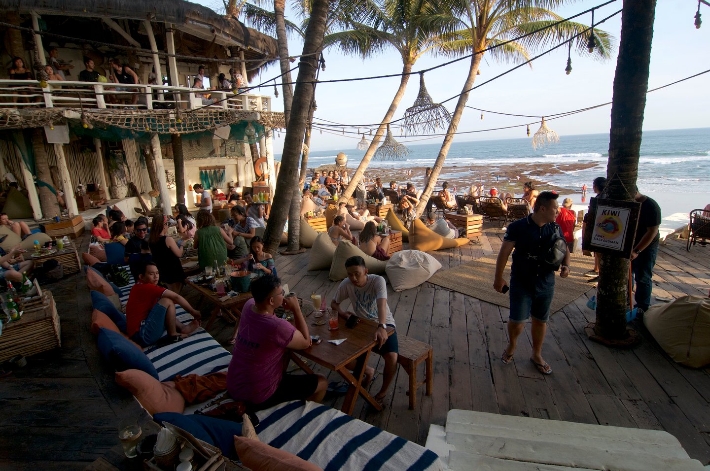  View on a beautiful beach restaurant terrace crowded with tourists at the famous Echo Beach in Canggu, Bali - Indonesia