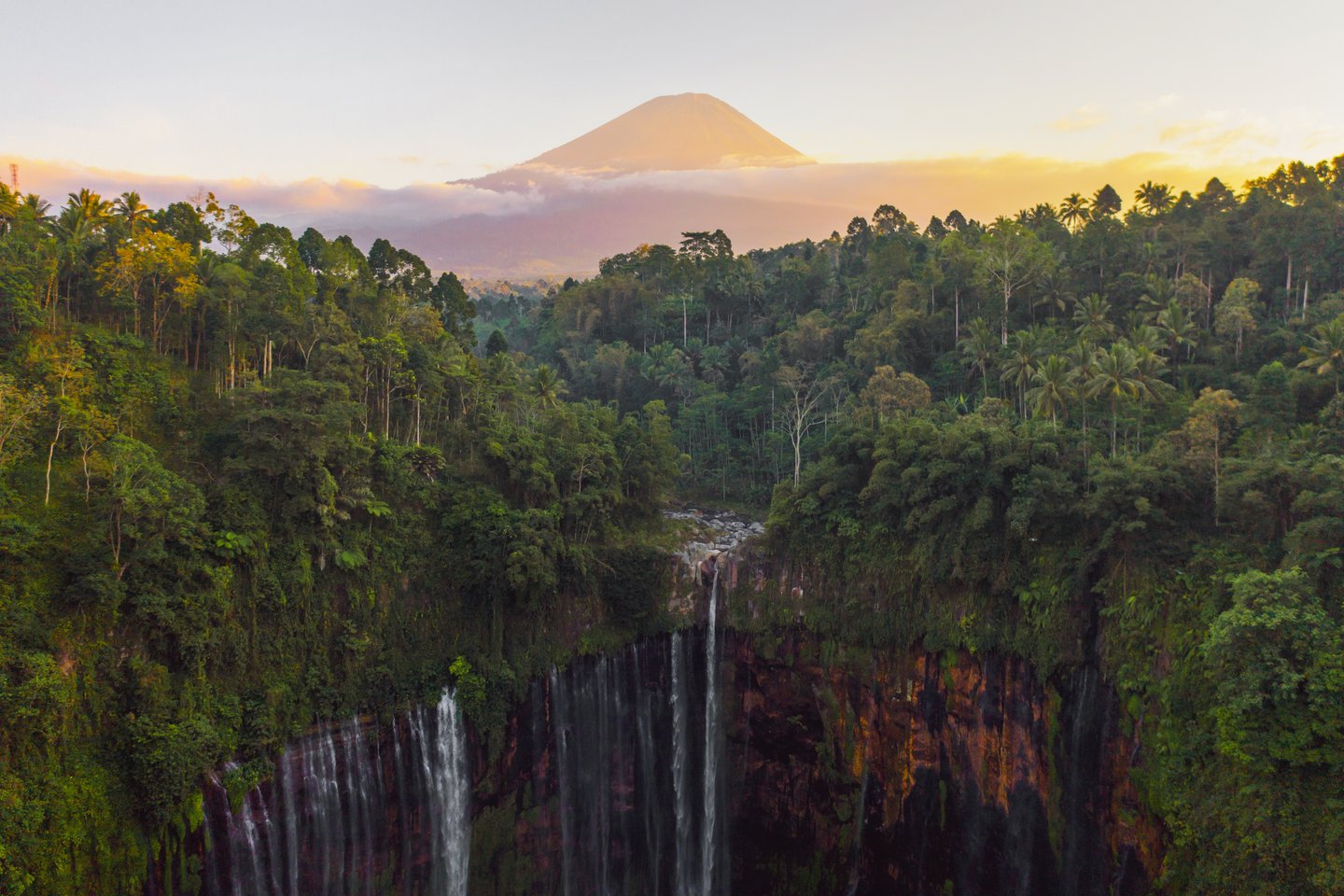 The forest and Tumpak Sewu waterfall with the volcano in the background