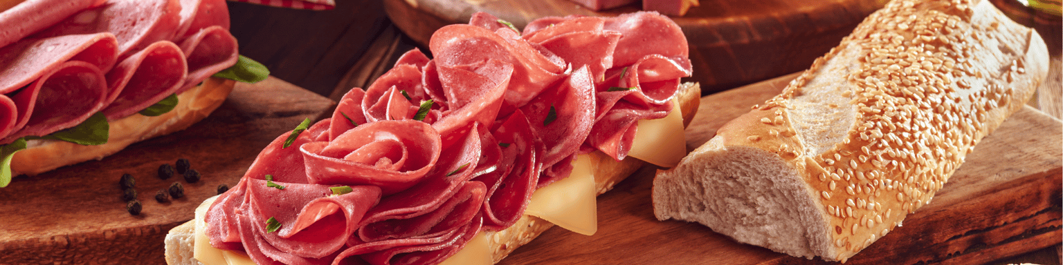 Mortadella sandwich with butter, bread and spices on wood cutting board