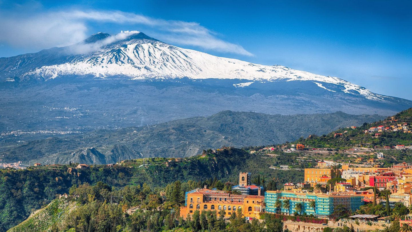 Mount Etna rising over Taormina town in Sicily, Italy.