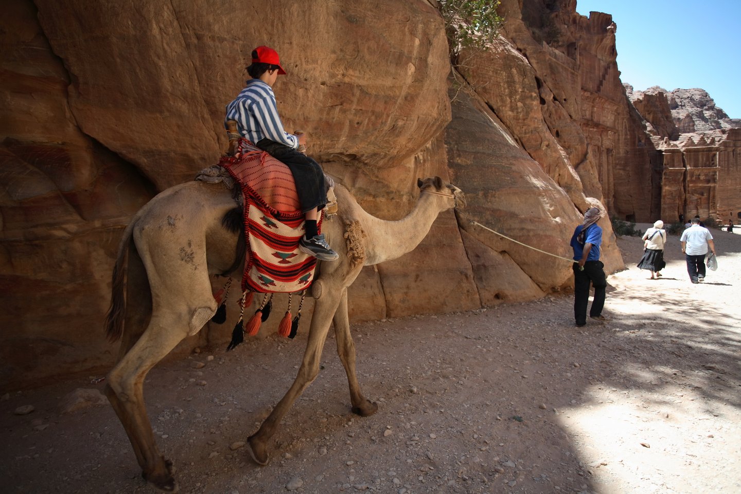 A boy riding a camel in the ancient city of Petra in Jordan.