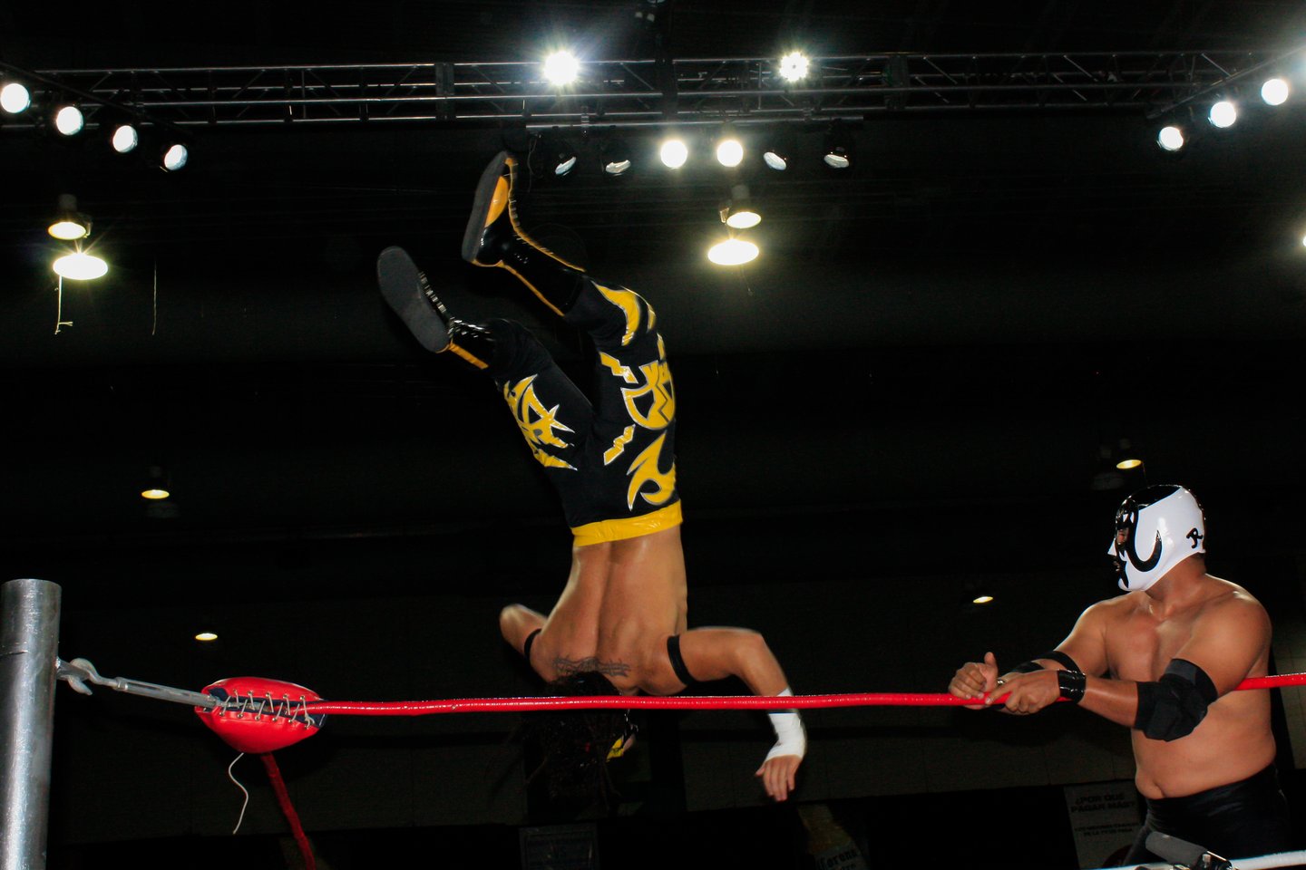 A wrestler flipping over the rope at lucha libre in Mexico city