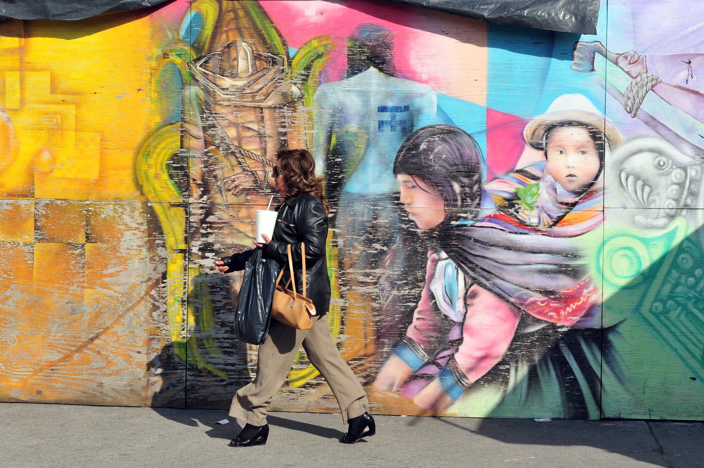 A woman walking past street art in Mexico City