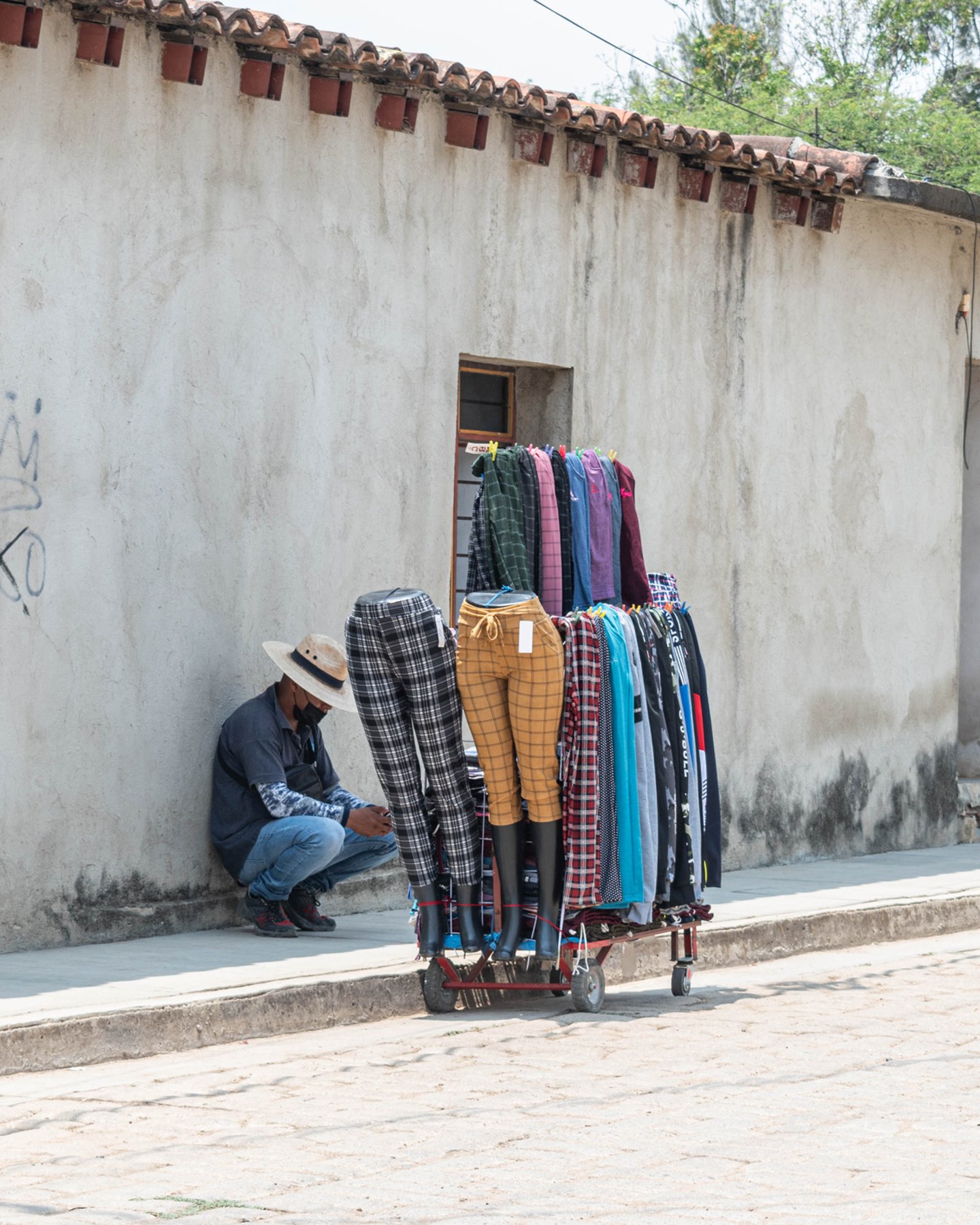 Crouching man selling clothes at the street in San Bartolo Coyotepec, Mexico